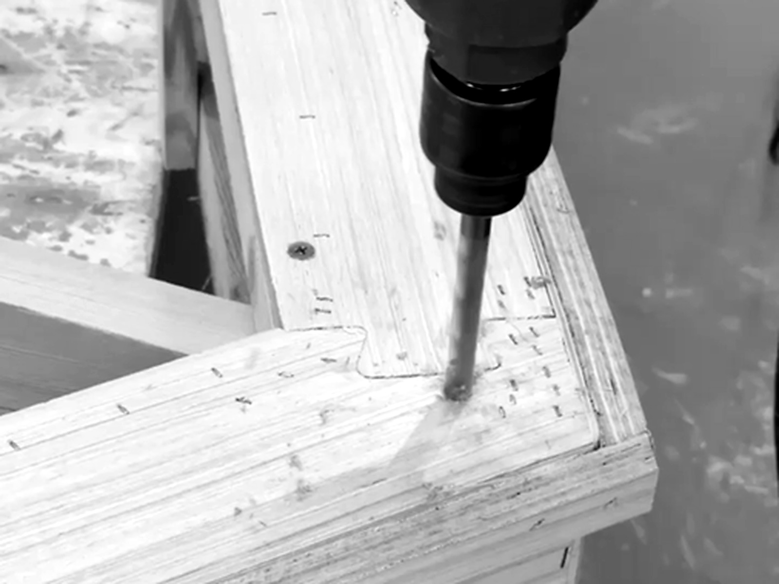 Close detail of a drill working into a timber furniture frame