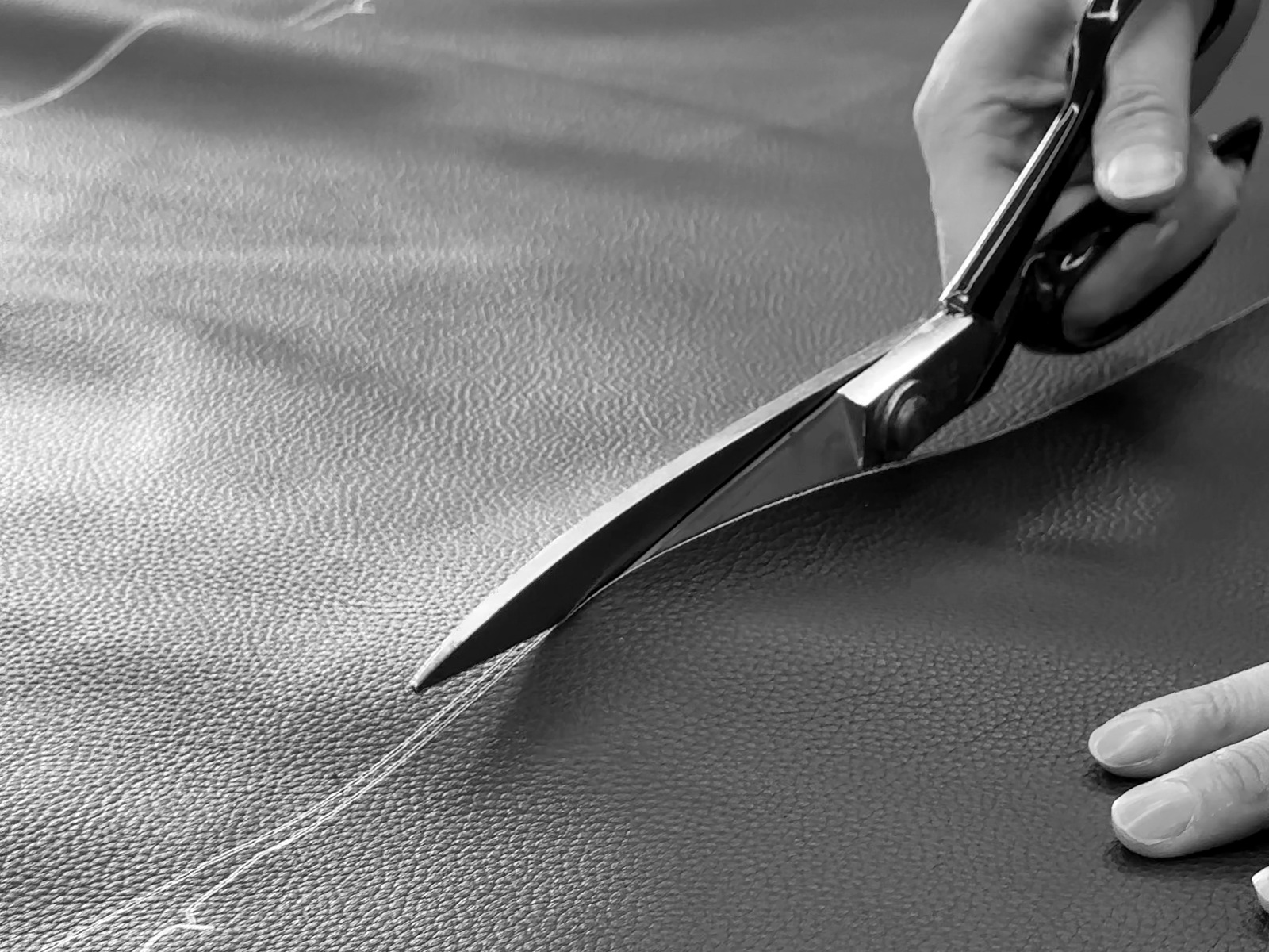 Close detail of hands cutting leather along a marked pattern