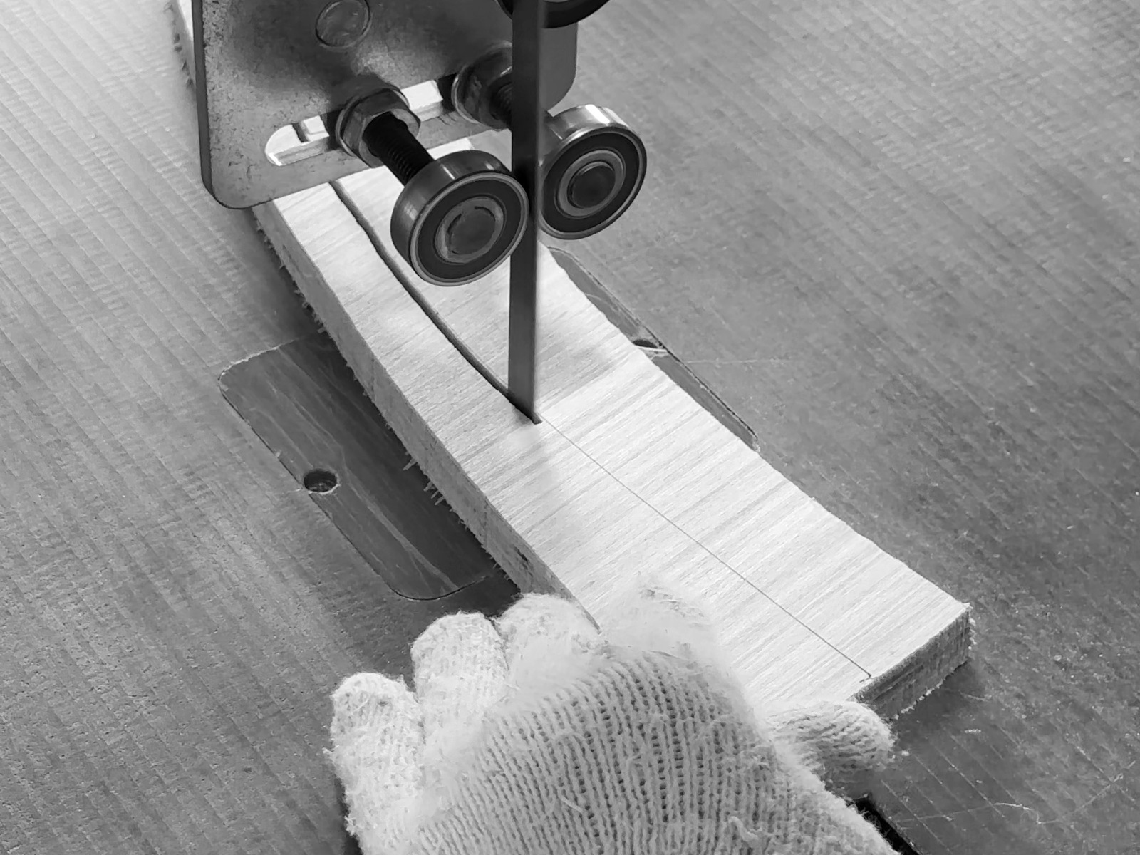 Close detail of a craftsman guiding timber through a band saw